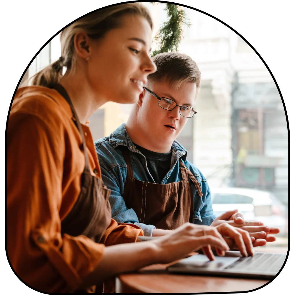 Support worker helping disabled man with down syndrome on laptop