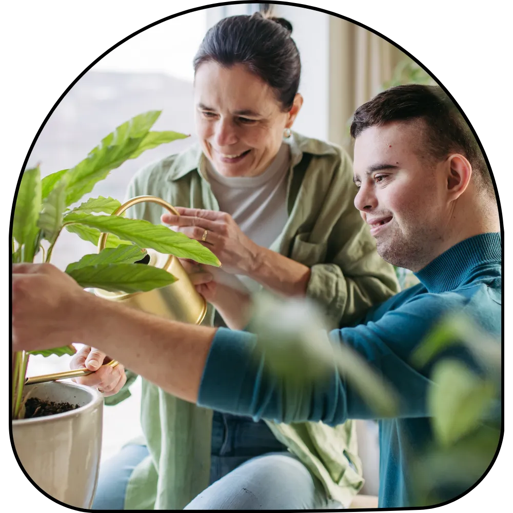 Disabled man with down syndrome watering plants with support worker