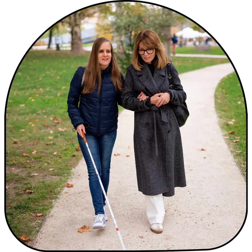 Blind woman walking with support worker in park