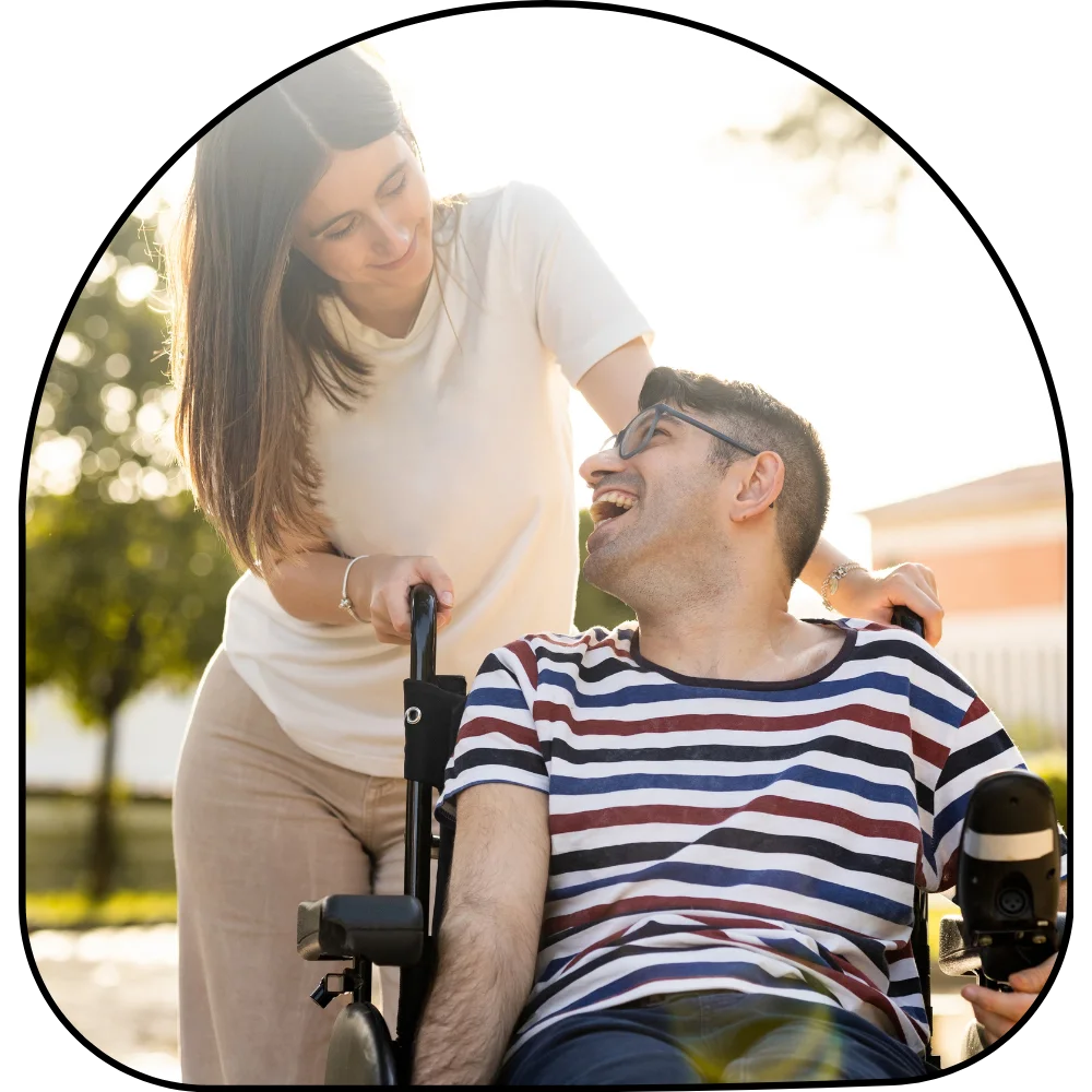 Disabled man in wheelchair happily smiling up at support worker